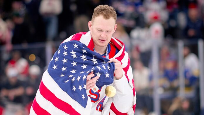 1772321408_brady-tkachuk-with-medal-usa-flag.jpg